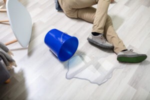 man on floor next to spilled bucket of water