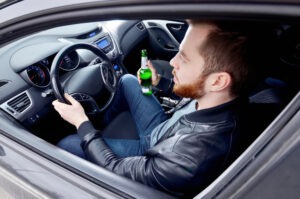 man driving with beer bottle